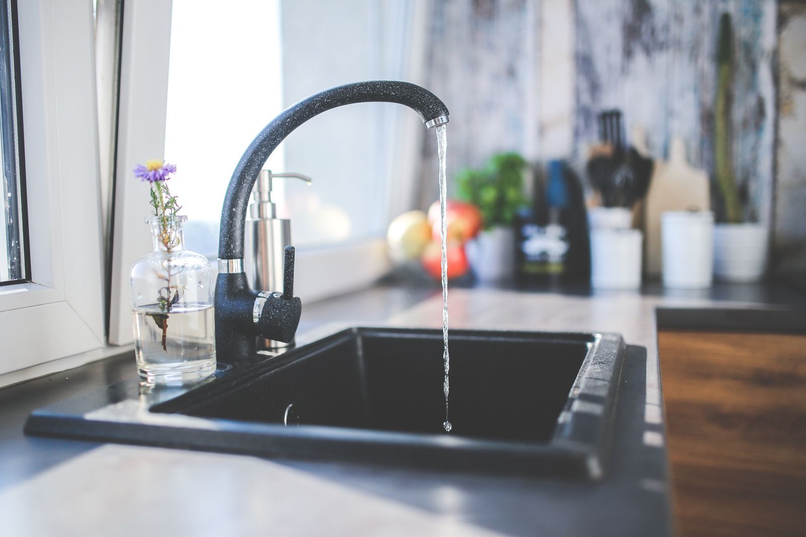 Water dat uit een keukenkraan in de spoelbak stroomt als illustratie bij aansluitwerken